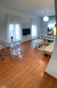 sala de estar con suelo de madera y mesa en Apartamento luminoso en Espartinas Totalmente climatizado, en Espartinas