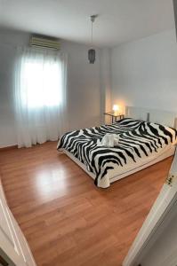 Cama con estampado de cebra en una habitación con suelo de madera en Apartamento luminoso en Espartinas Totalmente climatizado, en Espartinas