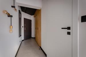 un couloir avec des murs blancs ainsi que des sols et des portes blancs dans l'établissement Apart Invest Centrum Park 2, à Szklarska Poręba