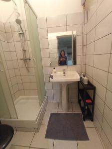 een badkamer met een wastafel en een douche en een persoon in de spiegel bij hébergement de la plage en ville in Martigues