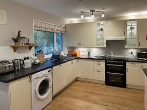 a kitchen with white cabinets and a washer and dryer at Tides Reach in Lamlash