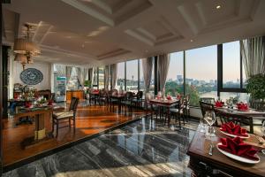 een eetkamer met tafels en stoelen en grote ramen bij San Grand Hotel & Spa in Hanoi