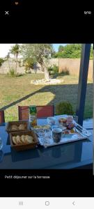 una mesa con una cesta de pan y comida. en Chambre d'hôtes Entre mer forêt et marais, en Olonne-sur-Mer