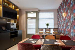 a dining room with tables and chairs and a tv at H&ocirc;tel Tourisme Avenue in Paris