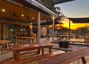 an outdoor patio with wooden tables and chairs at sunset at Vineyard stay at Mudgee in Apple Tree Flat