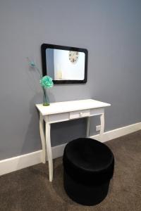 a white desk with a mirror and a black stool at East Shore in Hastings