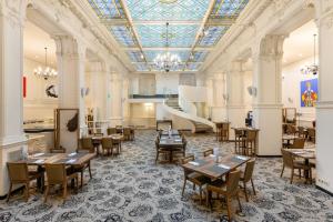 a dining room with tables and chairs and a ceiling at Hotel Nemzeti Budapest - MGallery in Budapest