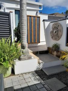 een veranda van een huis met een palmboom en planten bij Côté Terrasse in Le Tampon