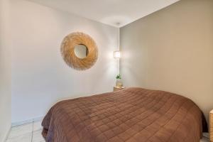 1 dormitorio con cama y espejo de mimbre en Gezellig en knus app vlakbij centrum Nieuwpoort!, en Nieuwpoort