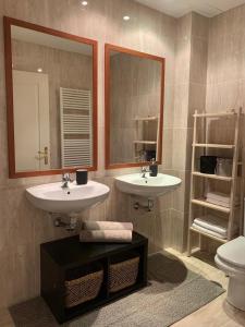 uma casa de banho com 2 lavatórios, um espelho e um WC em Sor Angela Apartment em Madri