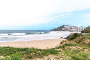 a sandy beach with waves in the ocean at APARTAMENTO PEDRADOURO in Malpica