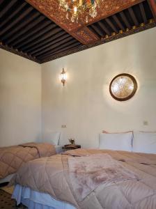 1 dormitorio con 2 camas y techo con espejo. en Dar Naima, en Fez