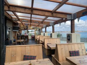 a restaurant with wooden tables and chairs and the water at Harbour House Inn Newcastle, Northern Ireland in Newcastle