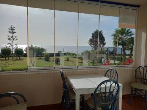 ein Esszimmer mit Tisch und Stühlen und einem Fenster in der Unterkunft Seafront Garden and Sea views in Torrox