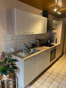 een keuken met witte kasten en een wastafel bij Ferienwohnung Schanz in Konken