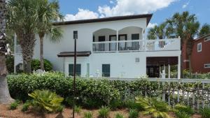 a white house with a balcony and palm trees at Dolphin House in Santa Rosa Beach