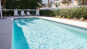 a blue swimming pool with chairs in a yard at Dolphin House in Santa Rosa Beach