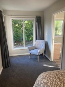 1 dormitorio con silla azul y ventana en Private Guest House, en Mapua
