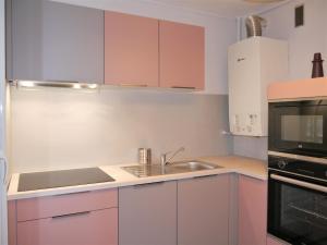 La cuisine est équipée de placards roses, d'un évier et d'un four micro-ondes. dans l'établissement Appartement Le Céleste 113 - deux chambres, à Ramonville-Saint-Agne