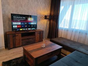 uma sala de estar com uma televisão, um sofá e uma mesa em Viva 4 Apartment ski to the door complex Grand Monastery Pamporovo em Pamporovo