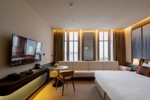 um quarto de hotel com uma cama, um sofá e uma televisão em Hotel MOCO em Udon Thani