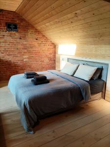 ein großes Bett in einem Zimmer mit Ziegelwand in der Unterkunft La Cense du Noir Jambon in Silly