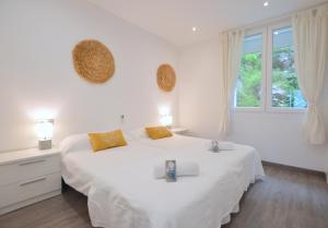 a white bedroom with a large white bed with yellow pillows at House 200m from Puerto de Sóller Beach in Sóller