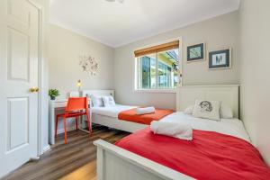 Un dormitorio con dos camas y un escritorio y una silla. en Sunflower Cottage, en Katoomba