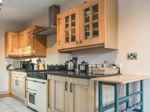 a kitchen with wooden cabinets and a counter top at Woodland Cottage in Pont Yates