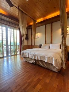 a bedroom with a large bed in a room with wooden floors at Cingjing Vienna Pleasance Cottage in Renai