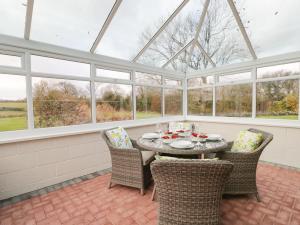 a conservatory with a table and chairs and windows at The Annex in Swindon