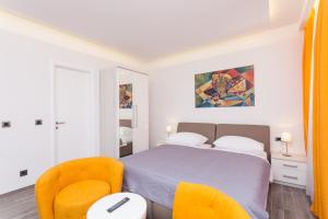 a bedroom with a bed and two orange chairs at Villa Peragro in Dubrovnik