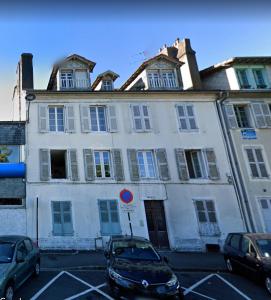 ein großes weißes Gebäude mit Autos auf einem Parkplatz in der Unterkunft L'Haussmann, Rare, Appartement Vue Château et Palmiers in Pau
