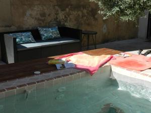 MaubecにあるLe Maset des Aires avec vue sur le Luberon et son jacuzzi extérieur disponible de juin à mi-septembreのプールの横にテーブルとソファが置かれたプール