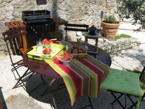 una mesa con un mantel colorido y una parrilla en Le Maset des Aires avec vue sur le Luberon et son jacuzzi extérieur disponible de juin à mi-septembre, en Maubec