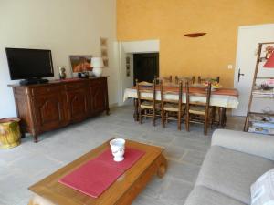 een woonkamer met een tafel en een televisie bij Le Maset des Aires avec vue sur le Luberon et son jacuzzi extérieur disponible de juin à mi-septembre in Maubec