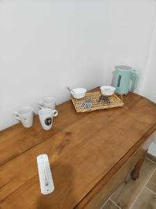 une table en bois avec quatre tasses au-dessus dans l'établissement Logement : 2 chambres (5 couchages), salle de bain, à Pierrefitte-sur-Sauldre