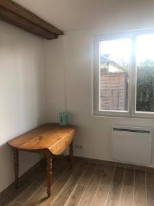 - une table en bois dans une chambre avec fenêtre dans l'établissement Logement : 2 chambres (5 couchages), salle de bain, à Pierrefitte-sur-Sauldre