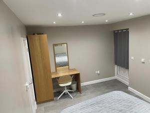 a bedroom with a desk and a mirror and a chair at One bedroom apartment in Goodmayes