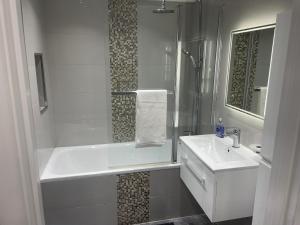 a white bathroom with a tub and a sink at One bedroom apartment in Goodmayes