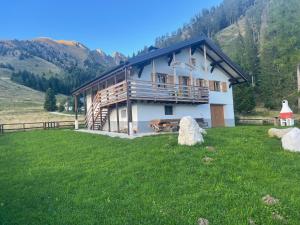a large house in a grassy field with a building at Chalet Paradisi in Castello Tesino