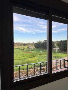 une fenêtre avec vue sur un champ verdoyant dans l'établissement Casa Rural "El Cañuelo", à Aljucén