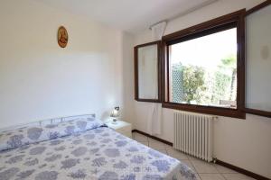 een slaapkamer met een bed en een raam bij VILLA MAGNOLIA vicino al mare in Isola Albarella
