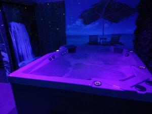 eine rosa Badewanne in einem Zimmer mit Sonnenschirm in der Unterkunft Virtuel Spa in Achicourt