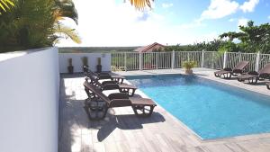 a pool with chaise lounge chairs and a swimming pool at VILLA ÉLISHA in Saint-Louis