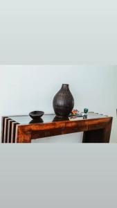 einen Holztisch mit einer Vase darüber in der Unterkunft Little Princess in Luanda