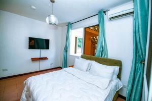 um quarto com uma cama branca e uma janela em Dafina Residence em Dar es Salaam