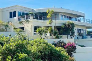 una casa blanca con palmeras delante en Villa with exquisite mountain and sea views…, en Ciudad del Cabo