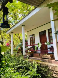 uma pequena casa branca com um alpendre e algumas plantas em Green Leaf Holiday Bungalow em Ratnapura