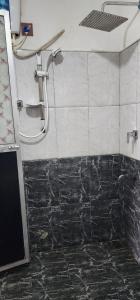 a shower in a bathroom with black and white tiles at Green Leaf Holiday Bungalow in Ratnapura
